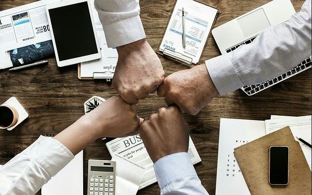 4 people giving each over fist pump duting during a meeting