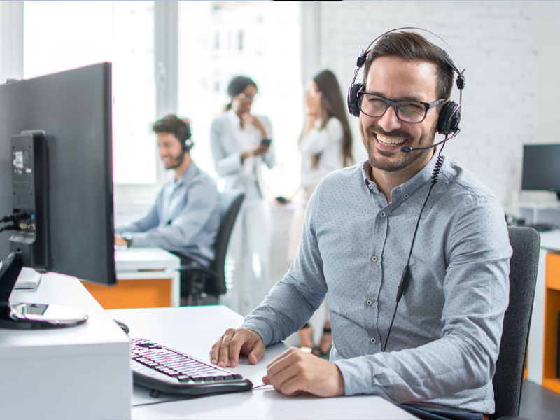 A person seated at a computer happily providing customer service.