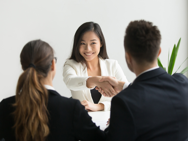 A person shaking hands at a job interview.
