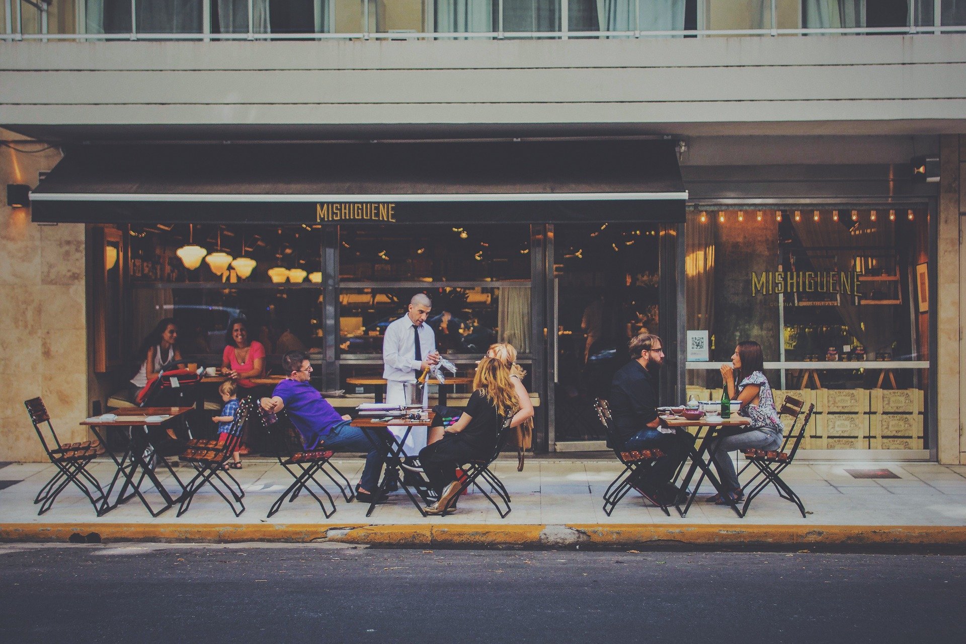 A group of people sitting and discussing outside a cafe
