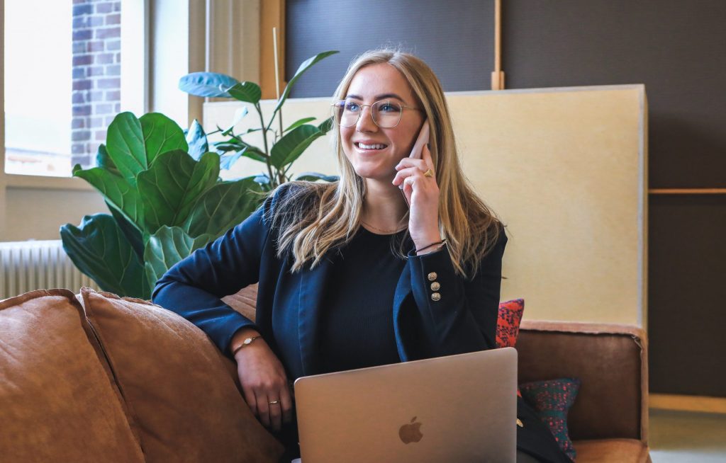 A person seated whilst on the telephone, smiling.