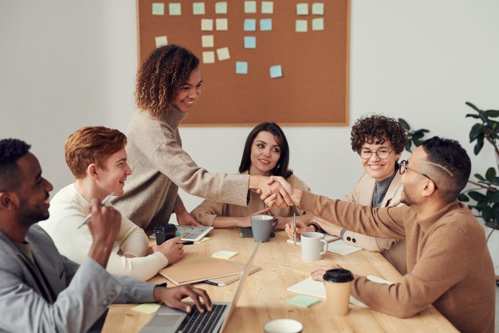 Multiple people seated at a meeting table displaying professional workplace behaviours.