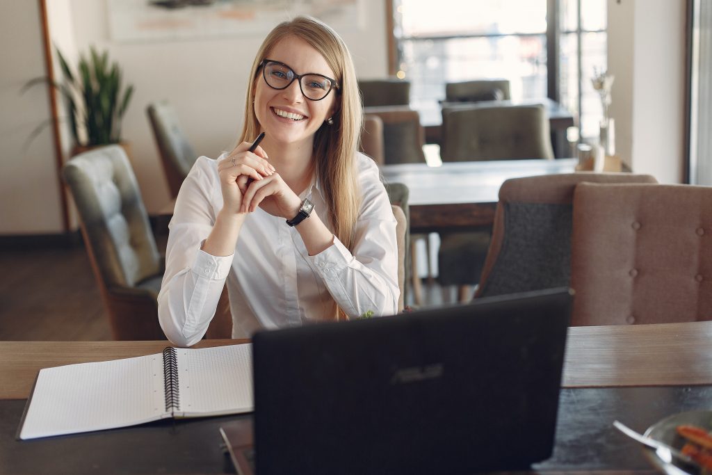 A person seated at a laptop, smiling.