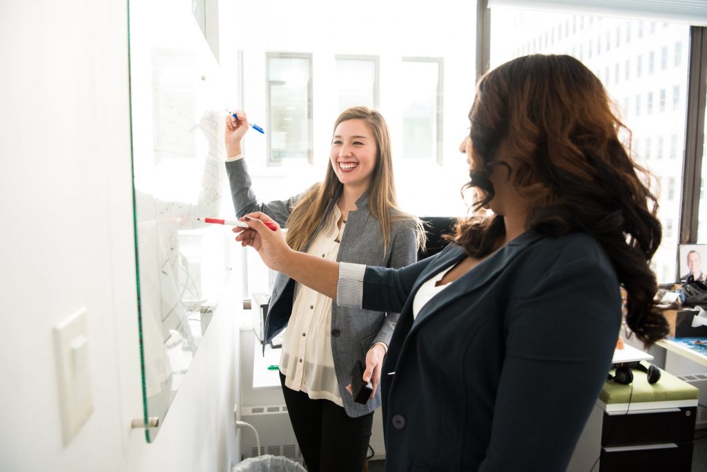 Two people brainstorming at a whiteboard.