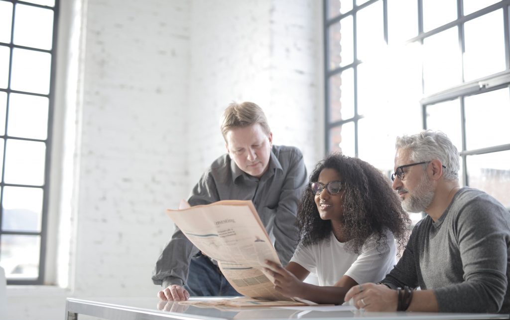 Three people working collaboratively to review a document.