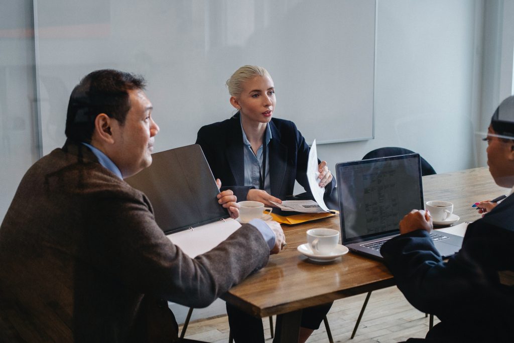 Three people seated at a table involved in a business meeting.