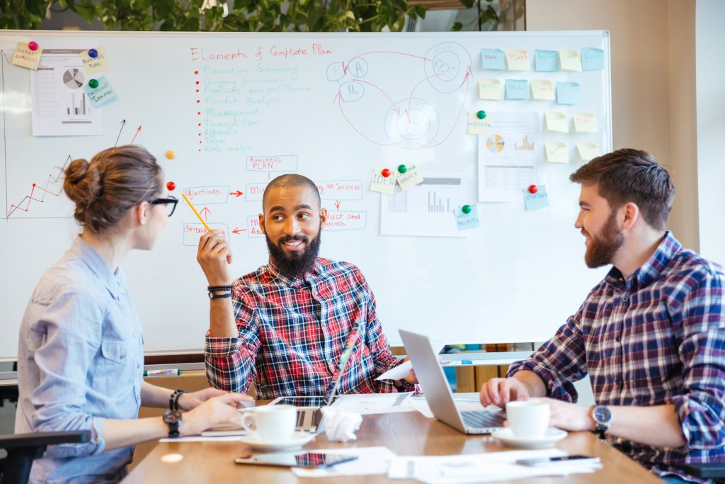 Three people seated at a table brainstorming a new plan.