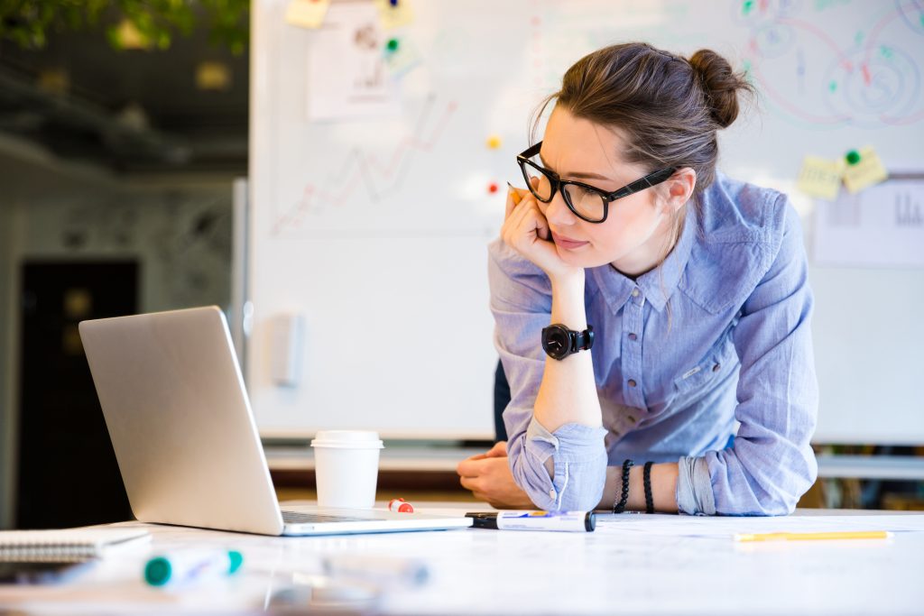 A person seated at a laptop looking perplexed.