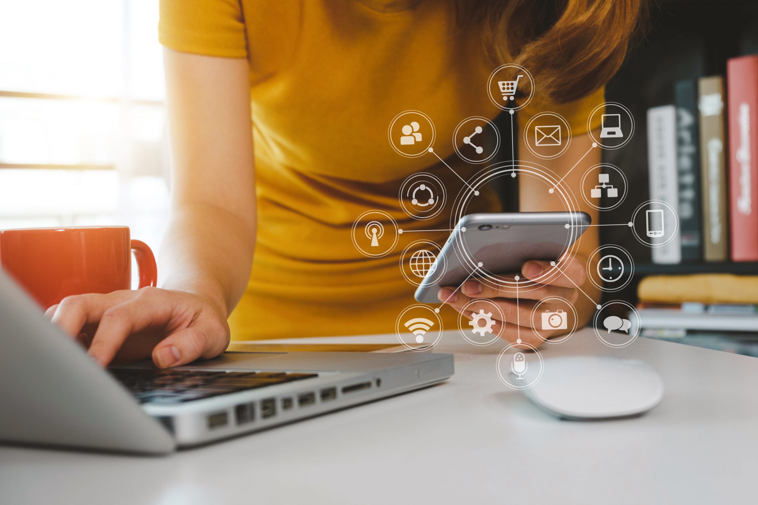 A person working on the laptop and mobile with futuristic graphic floating on the image