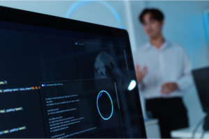 A focus on computer screen with a worker ont he background.